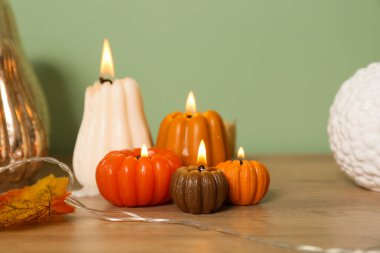 Balkabağı şeklinde mumlar ve sonbahar yaprakları evdeki yeşil duvarın yanında klozette yanıyor.