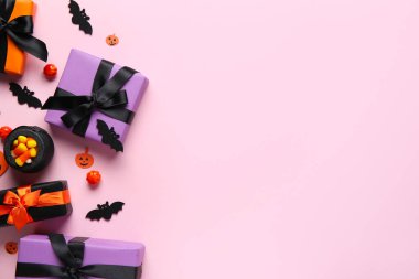 Cadılar Bayramı hediyeleri, balkabakları, yarasalar ve pembe arka planda şekerler. Üst görünüm