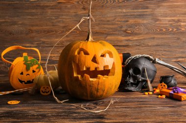 Kahverengi ahşap arka planda balkabağı oyulmuş çanta ve süslemeler