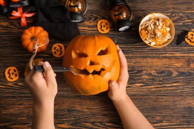 Süslü bir kadın, bir kase tohum ve bıçakla Cadılar Bayramı için balkabağı oyma kahverengi ahşap arka planda