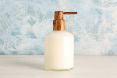 Mavi grunge duvarının yanındaki beyaz masada sabun makinesi.