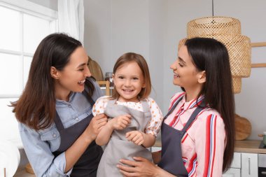 Mutfakta evlatlık küçük kızı olan genç lezbiyen çift.