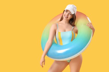 Sarı arka planda yüzme yüzüğü olan genç bir kadın.