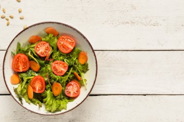 Hafif ahşap arka planda taze sebze salatası.