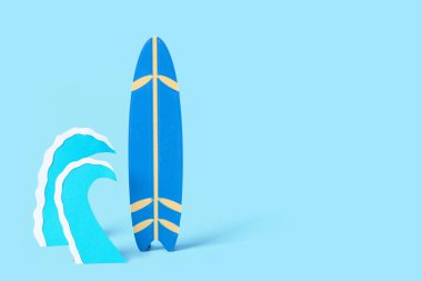 Mavi zemin üzerinde kağıt dalgaları ve mini sörf tahtası olan yaratıcı kompozisyon