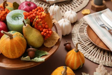 Kahverengi arkaplanda sonbahar dekoru ve mumlarla süslü masa ayarları