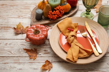 Sonbahar masası, balkabakları, altın çatal bıçaklar ve beyaz ahşap masa üzerinde yabanmersini servisi, yakın plan.