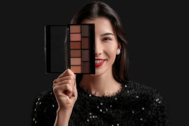 Siyah arka planda göz falı olan güzel bir genç kadın.