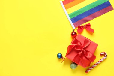 LGBT bayrağı, yay, Noel topları, hediye ve şeker kamışları sarı arka planda