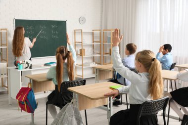 Sınıfta ders sırasında ellerini kaldırmış bir grup çocuk.