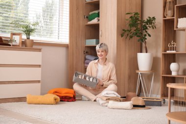 Ajandası ve evde yığınla giysisi olan güzel genç bir kadın.