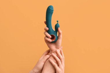 Renk arkaplanına karşı vibratörlü kadın elleri, yakın plan