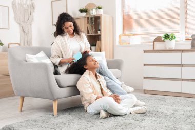 Genç Afro-Amerikalı kadın evde saçını tarıyor.