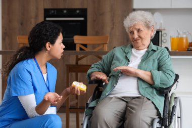 Huzurevindeki genç Afro-Amerikalı kadın sağlık çalışanının haplarını reddeden yaşlı bir kadın.