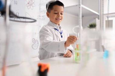 Fen sınıfında kimya şişeleri olan şirin bir çocuk.