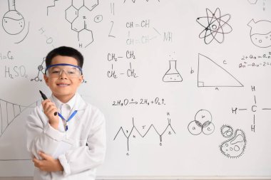 Kimya sınıfında beyaz tahtanın yanında tatlı bir çocuk.