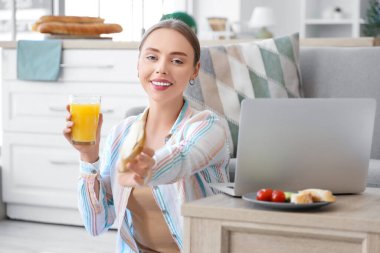 Güzel, genç, mutlu bir kadın elinde meyve suyu ve tereyağlı taze ekmek tutuyor.