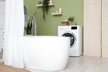 Modern banyonun içinde perde ve çamaşır makinesi olan küvet.