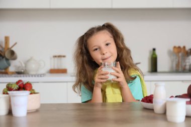 Mutfakta yoğurt içen küçük tatlı bir kız.