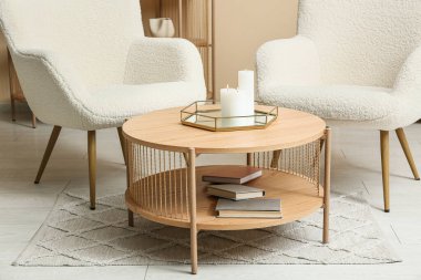 Koltukları, kahve masası ve yanan mumları olan modern oturma odasının içinde.