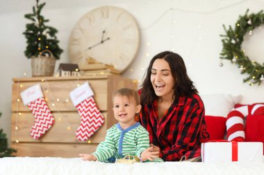 Mutlu anne ve küçük bebeği Noel arifesinde yatak odasında.