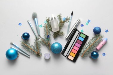 Dekoratif kozmetik ürünleri, makyaj aksesuarları ve hafif arka planda Noel süslemeleri olan kompozisyon