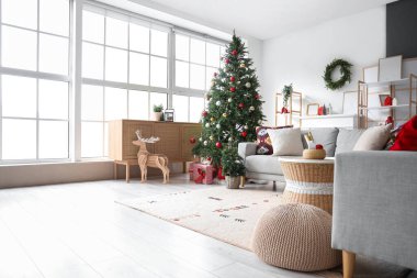 İçinde gri kanepe, Noel ağacı, hediye kutuları ve şenlikli süslemeler olan oturma odası.