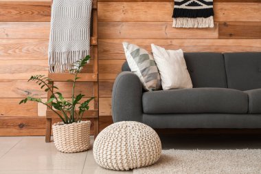 Gri kanepeli, puf ve ahşap merdivenli şık bir oturma odası.