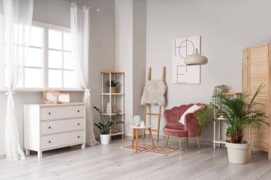 Ahşap merdiveni, koltuğu ve raf üniteleriyle aydınlık oturma odasının içinde.