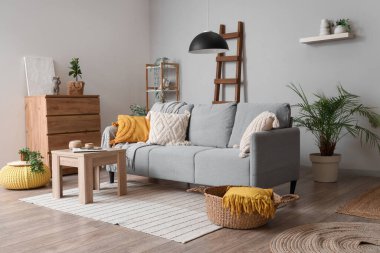 Ahşap merdiven, kanepe ve bitkilerle aydınlık oturma odasının içinde.