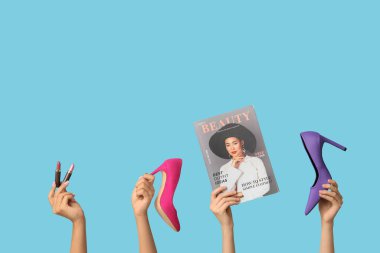 Şarjörlü kadın elleri, farklı topuklu ayakkabılar ve mavi arka planda ruj.