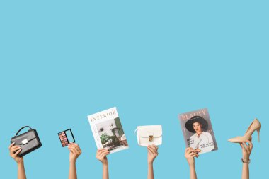 Farklı dergilere sahip kadın elleri, yüksek topuklu ayakkabılar, şık çantalar ve mavi arka plandaki göz falı paletleri.