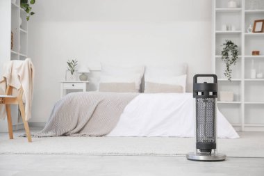 Yatak odasında yerde elektrikli ısıtıcı var.