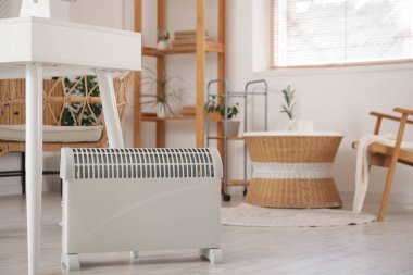 Oturma odasındaki masanın yanındaki katta elektrikli ısıtıcı, yakın çekim.