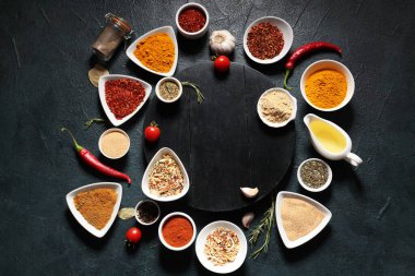 Composition with wooden board and different spices on dark color background