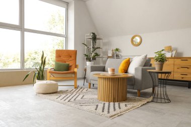 Ayna, gri kanepe ve koltuklu aydınlık oturma odasının içi.