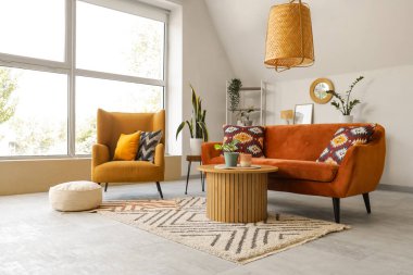 Ayna, kırmızı kanepe ve koltuklu aydınlık oturma odasının içi.