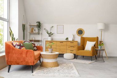 Ayna, kırmızı kanepe ve koltuklu aydınlık oturma odasının içi.