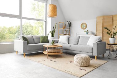 Ayna, gri kanepeler ve katlanan ekran ile aydınlık oturma odasının içi