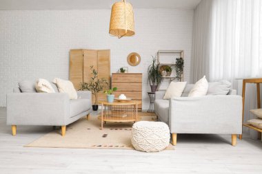 Ayna, gri kanepeler ve çekmeceleri olan oturma odasının içinde.