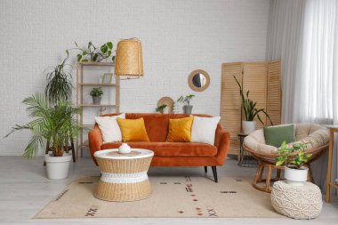 Oturma odasının içinde ayna, kırmızı kanepe ve bitkiler var.