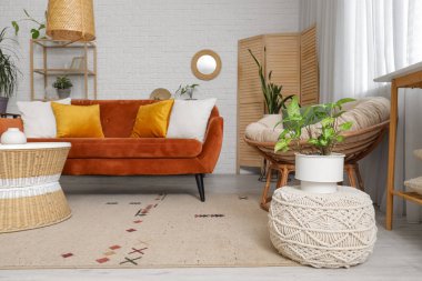 Oturma odasının içinde ayna, kırmızı kanepe ve bitkiler var.