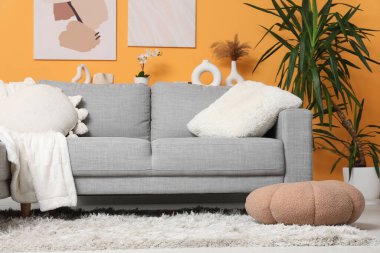 Gri kanepe, yumuşak puf ve halısı olan şık bir oturma odası.