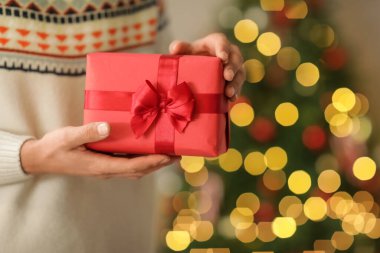 Evdeki Noel ağacının yanında hediye kutusu veren adam, yakın plan.