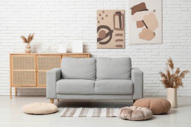 Konforlu kanepe, puflar ve pampalar vazonun içinde oturma odasının içinde.