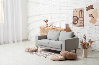 Konforlu kanepe, puflar ve pampalar vazonun içinde oturma odasının içinde.