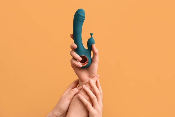 Женские руки с вибратором на цветном фоне, крупным планом