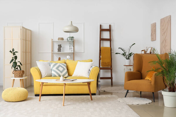 Interior of living room with wooden ladder, yellow sofa and armchair
