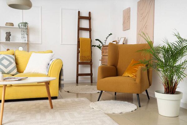 Интерьер гостиной с деревянной лестницей, желтым диваном и креслом