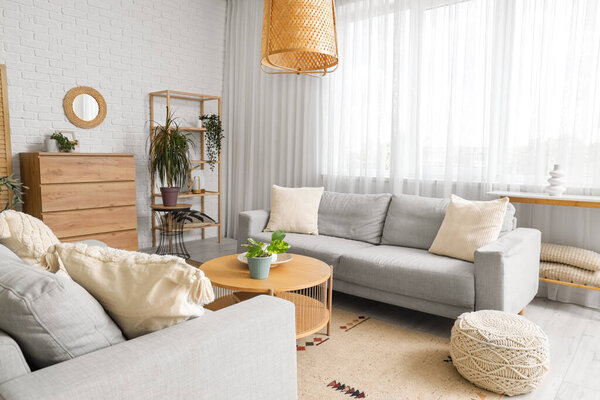 Interior of living room with mirror, grey sofas and drawers